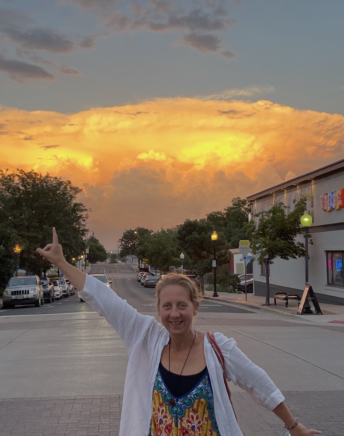 Ashley standing beneath a dramatic golden sunset sky